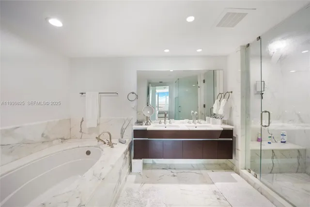 a large white bathroom with a large tub a sink and shower