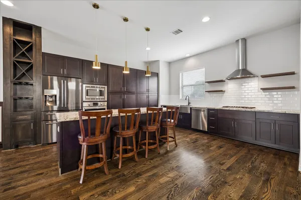 a kitchen with stainless steel appliances kitchen island granite countertop a table chairs sink and cabinets
