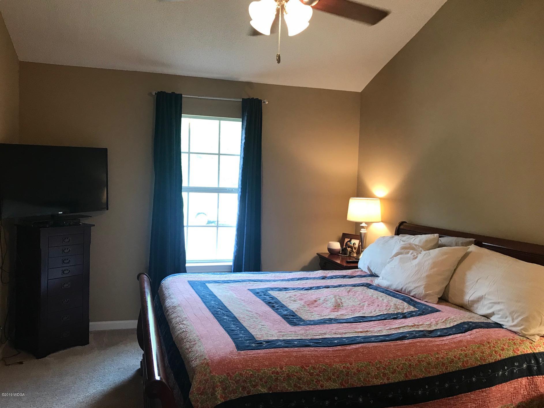 255 Autumn Ridge Court Gray, GA 31032 - Photo 8 of 16 a bedroom with a bed and a chandelier