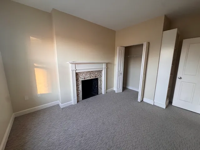 a view of an empty room with a window and fireplace