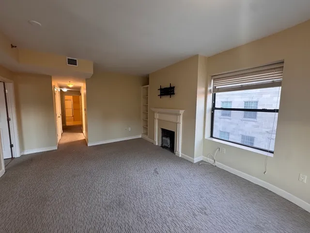an empty room with windows and fireplace