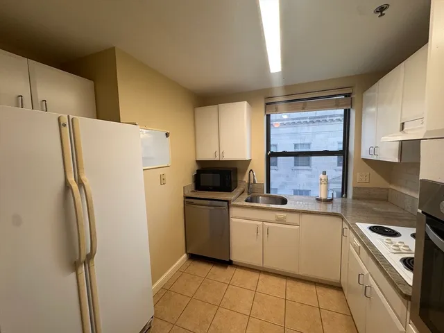 a kitchen with a refrigerator sink and white cabinets