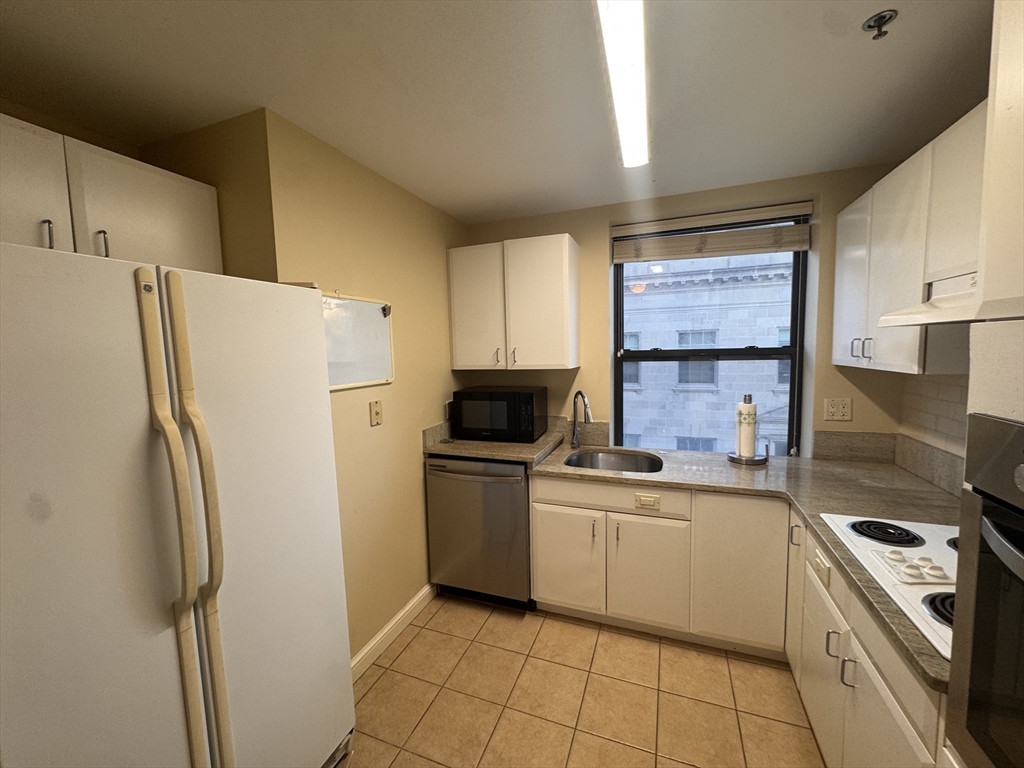 636 Beacon Street, Unit 404 Boston, MA 02215 - Photo 9 of 20 a kitchen with a refrigerator sink and white cabinets