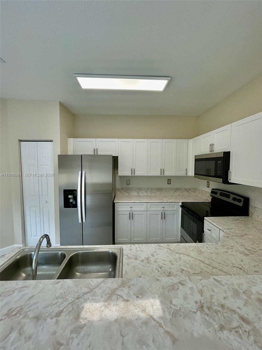 24651 Southwest 110th Avenue Homestead, FL 33032 - Photo 7 of 26 a kitchen with granite countertop a refrigerator and a sink