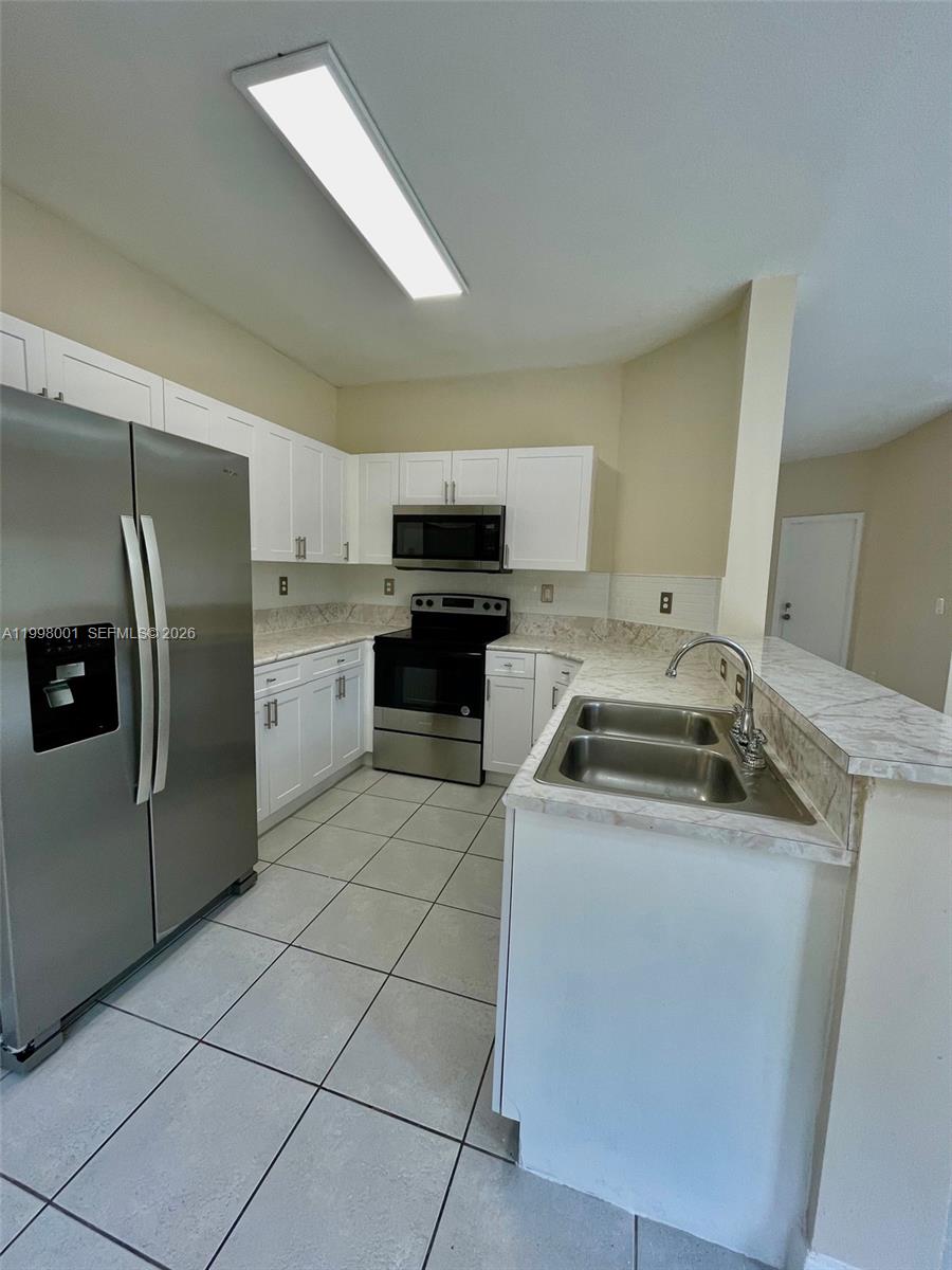 24651 Southwest 110th Avenue Homestead, FL 33032 - Photo 9 of 26 a kitchen with a sink a stove and refrigerator