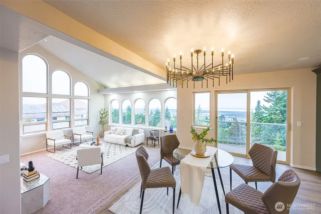 a view of a dining room with furniture a chandelier and large windows