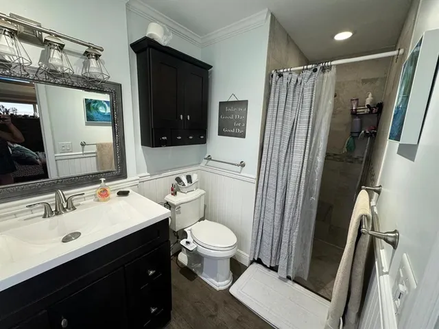 a bathroom with a sink a toilet a mirror and shower