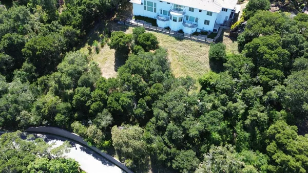 an aerial view of residential house with outdoor space and trees all around