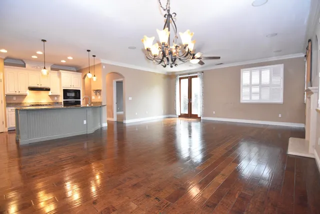 a view of a room with wooden floor kitchen chandelier and windows