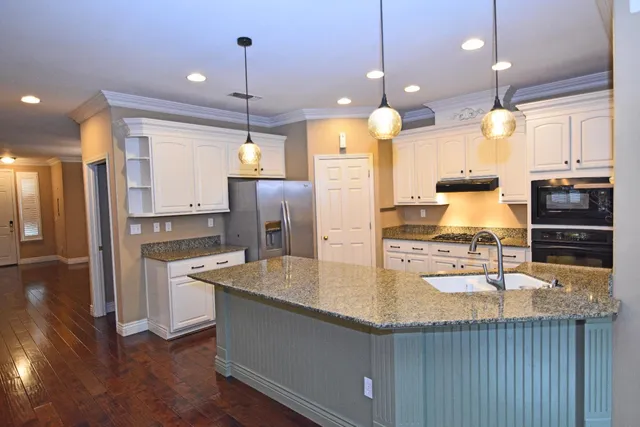 a kitchen with kitchen island a counter top space a sink appliances and cabinets