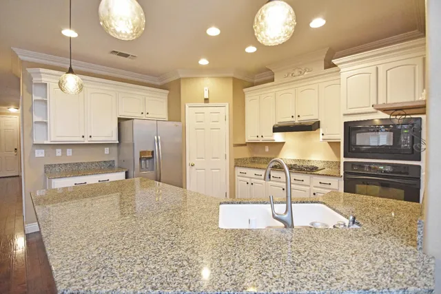 a kitchen with stainless steel appliances granite countertop a sink refrigerator and cabinets