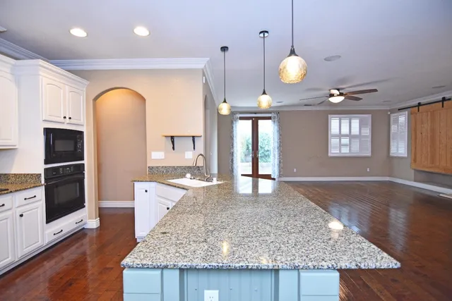 a large kitchen with granite countertop a stove a sink and a wooden floor