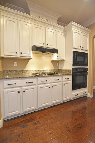 a kitchen with granite countertop white cabinets and stainless steel appliances