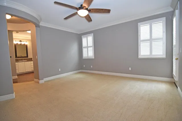 an empty room with chandelier fan and windows