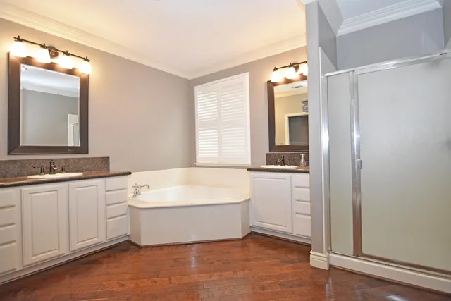 a spacious bathroom with a double vanity sink mirror and bathtub