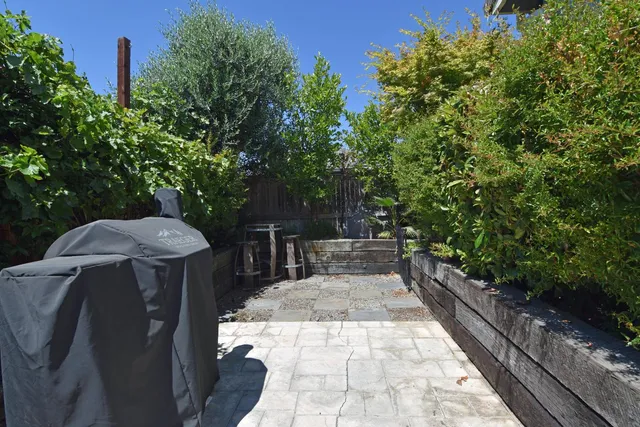 a view of a backyard with table and chairs potted plants with wooden wall