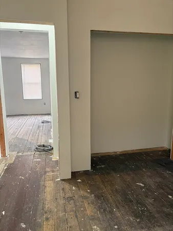 an empty room with wooden floor and a mirror