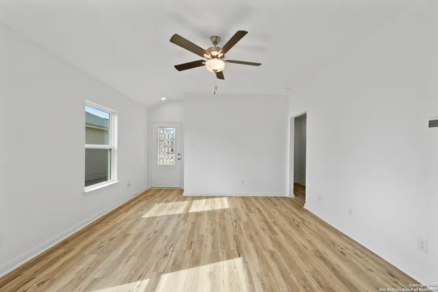a view of empty room with wooden floor and ceiling fan