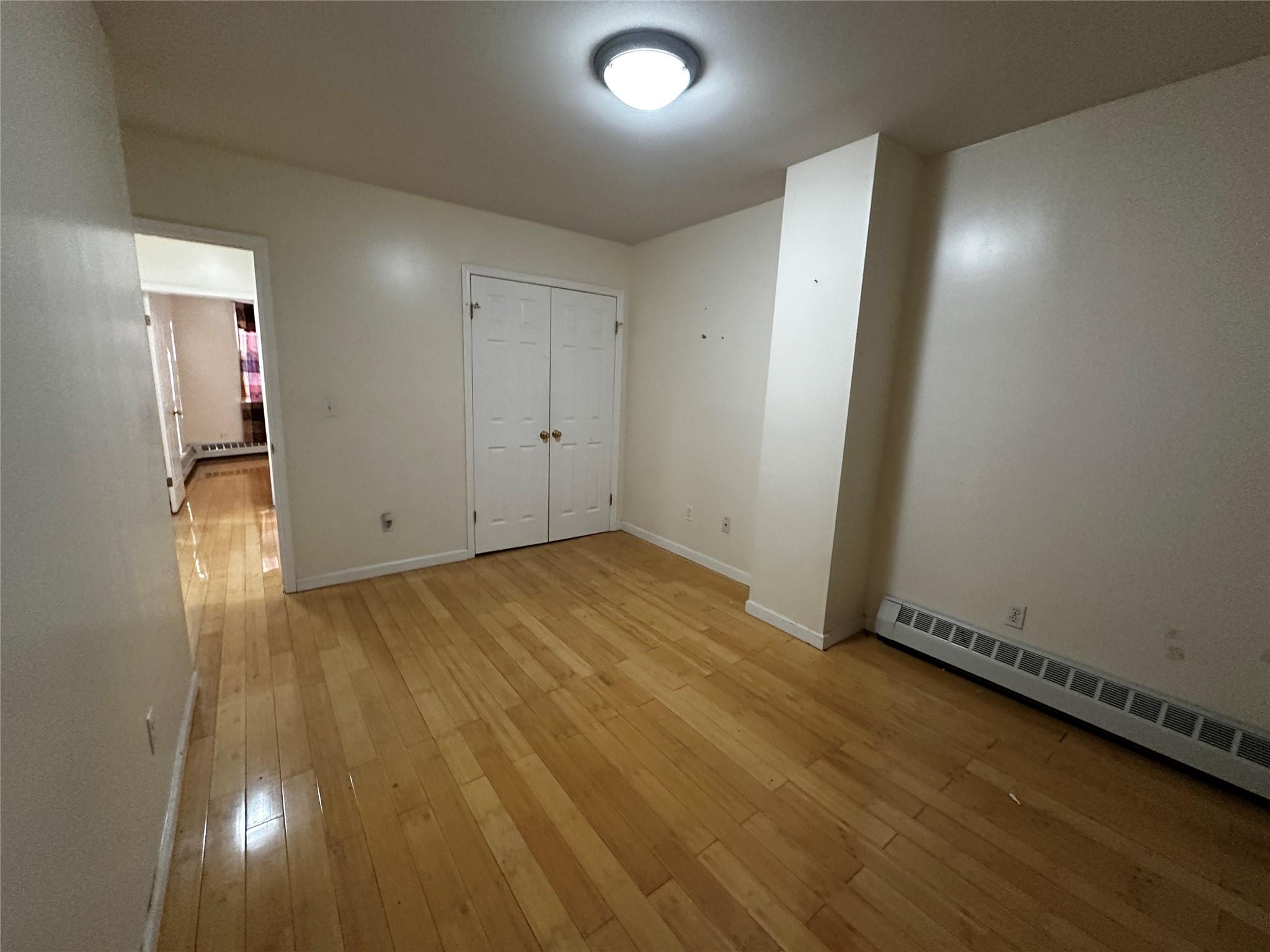 1316 Myrtle Avenue Brooklyn, NY 11221 - Photo 29 of 32 2ND FLRUnfurnished bedroom with a baseboard radiator, light hardwood / wood-style flooring, and a closet
