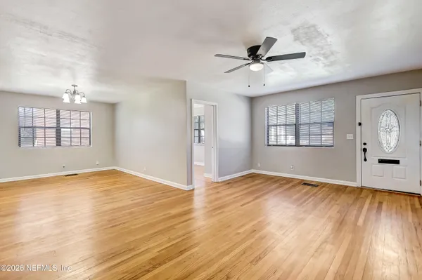 a view of empty room with wooden floor and fan
