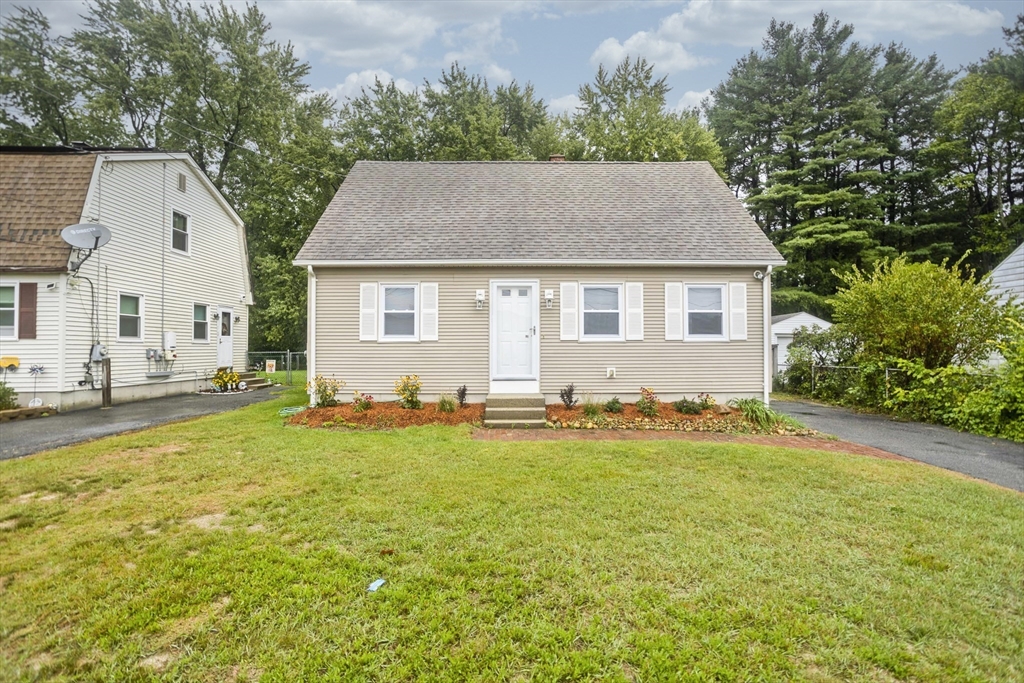 a front view of house with yard and trees in the background