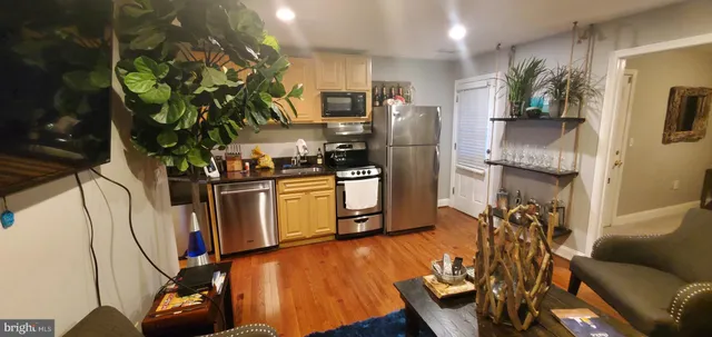 a kitchen with stainless steel appliances granite countertop a refrigerator a stove a sink dishwasher and a stove with wooden floor