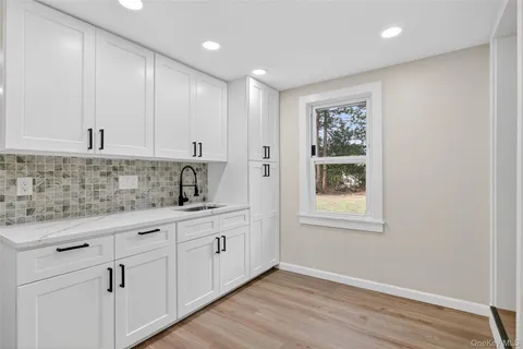 a kitchen with white cabinets and sink