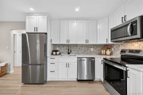 a kitchen with stainless steel appliances granite countertop a refrigerator stove a sink and white cabinets