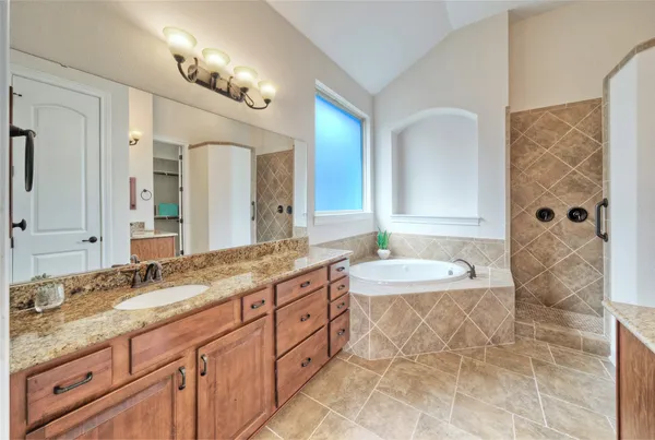 a bathroom with a granite countertop double vanity sink mirror and shower