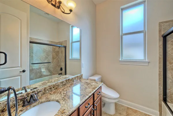 a bathroom with a granite countertop sink a toilet and mirror