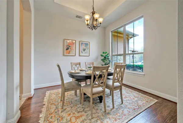 a dining room with wooden floor a chandelier a wooden table and chairs
