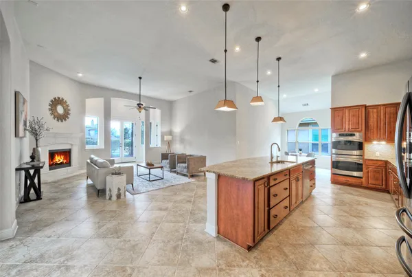 a large kitchen with stainless steel appliances kitchen island granite countertop a stove a sink a refrigerator and a fireplace