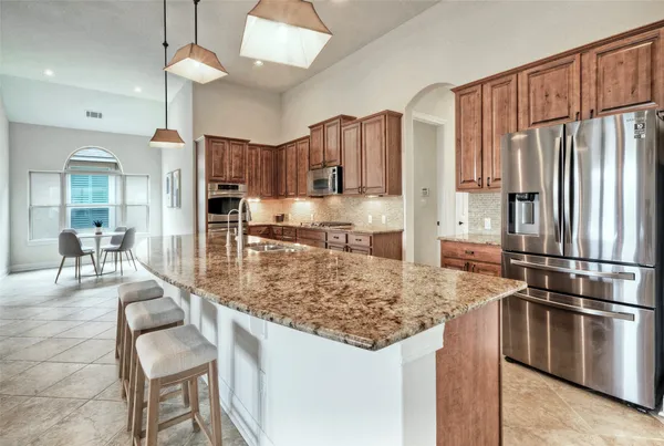 a kitchen with stainless steel appliances granite countertop a stove refrigerator sink and microwave