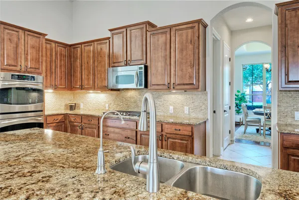 a kitchen with stainless steel appliances granite countertop a stove a sink a microwave and a refrigerator