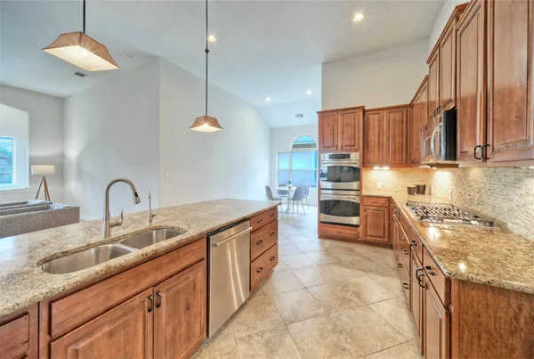 a kitchen with stainless steel appliances granite countertop a sink a stove and a refrigerator