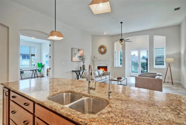 a kitchen with granite countertop a sink a counter top space cabinets and stainless steel appliances