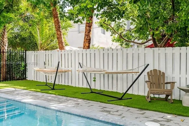a view of swimming pool with lawn chairs and plants