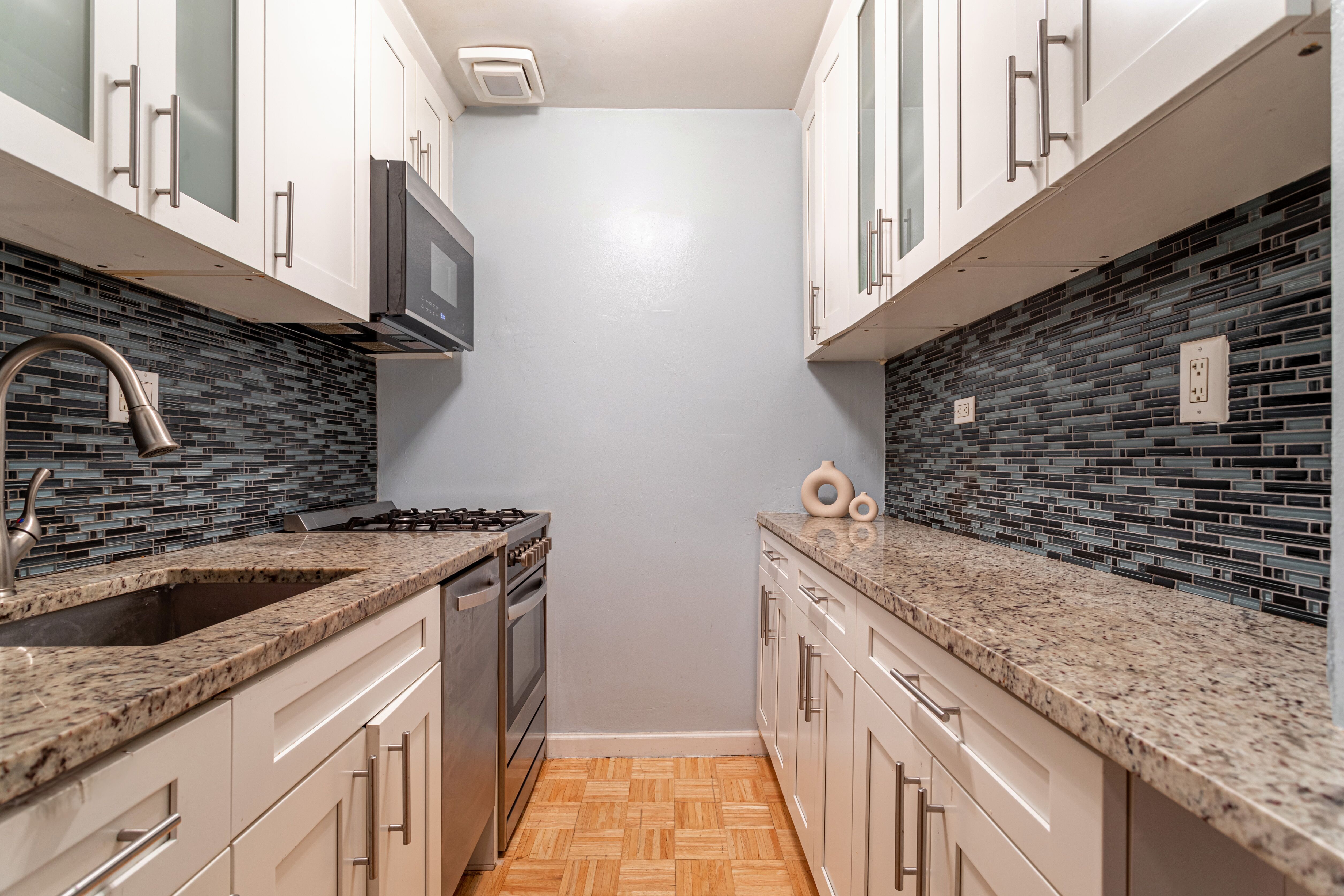 65-15 38th Avenue, Unit 2A Queens, NY 11377 - Photo 8 of 16 a kitchen with granite countertop a sink stove and cabinets