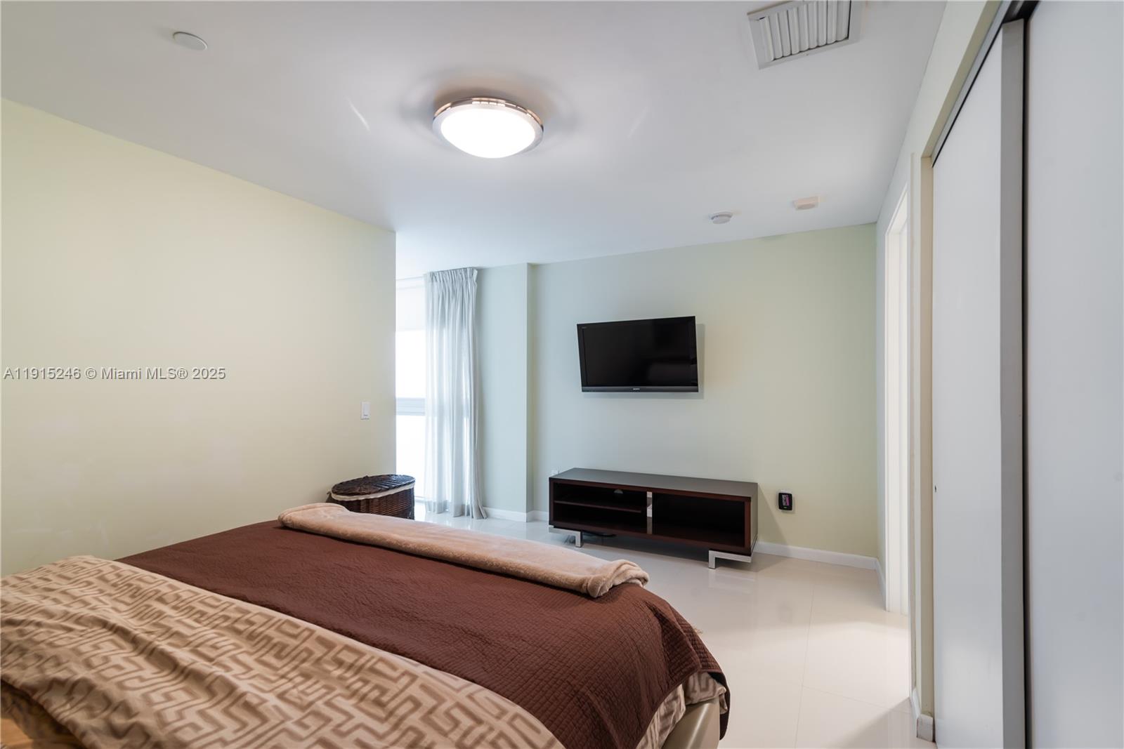 2950 Northeast 188th Street, Unit 504 Aventura, FL 33180 - Photo 17 of 33 a bedroom with a bed and a flat screen tv