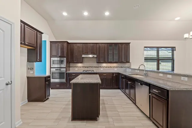 a kitchen with stainless steel appliances granite countertop a stove a sink dishwasher a refrigerator and a oven