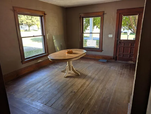 an empty room with wooden floor cabinet and windows