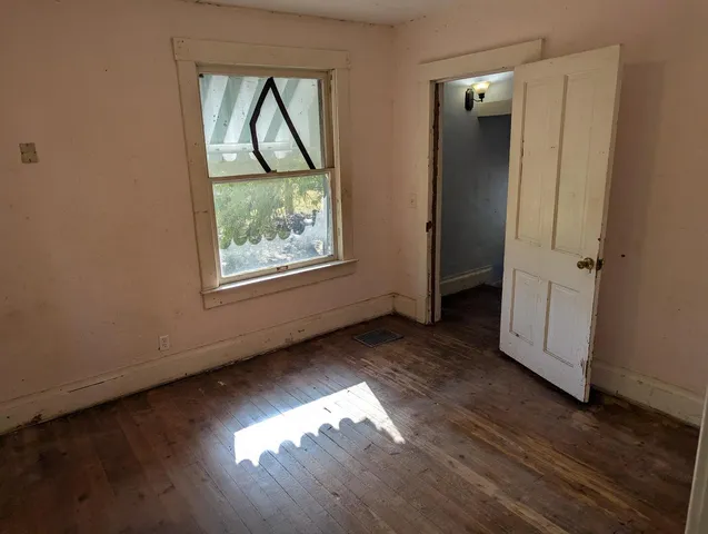 an empty room with wooden floor closet and windows