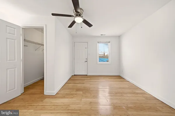 a view of empty room with wooden floor and ceiling fan