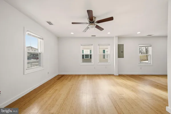 a view of empty room with wooden floor and fan