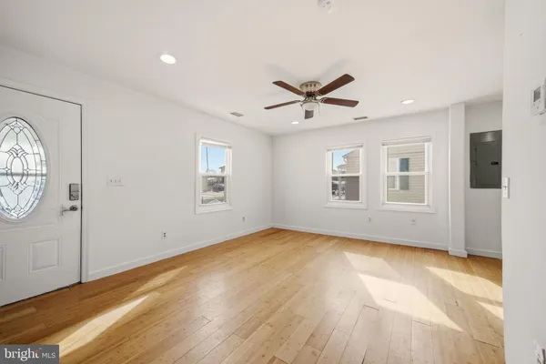 a view of an empty room with window and wooden floor