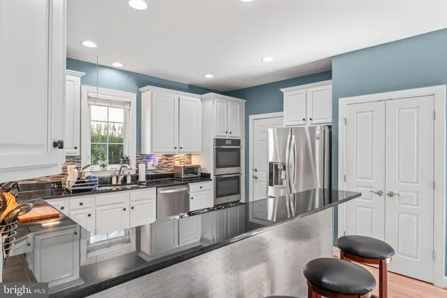 a kitchen with white cabinets and sink