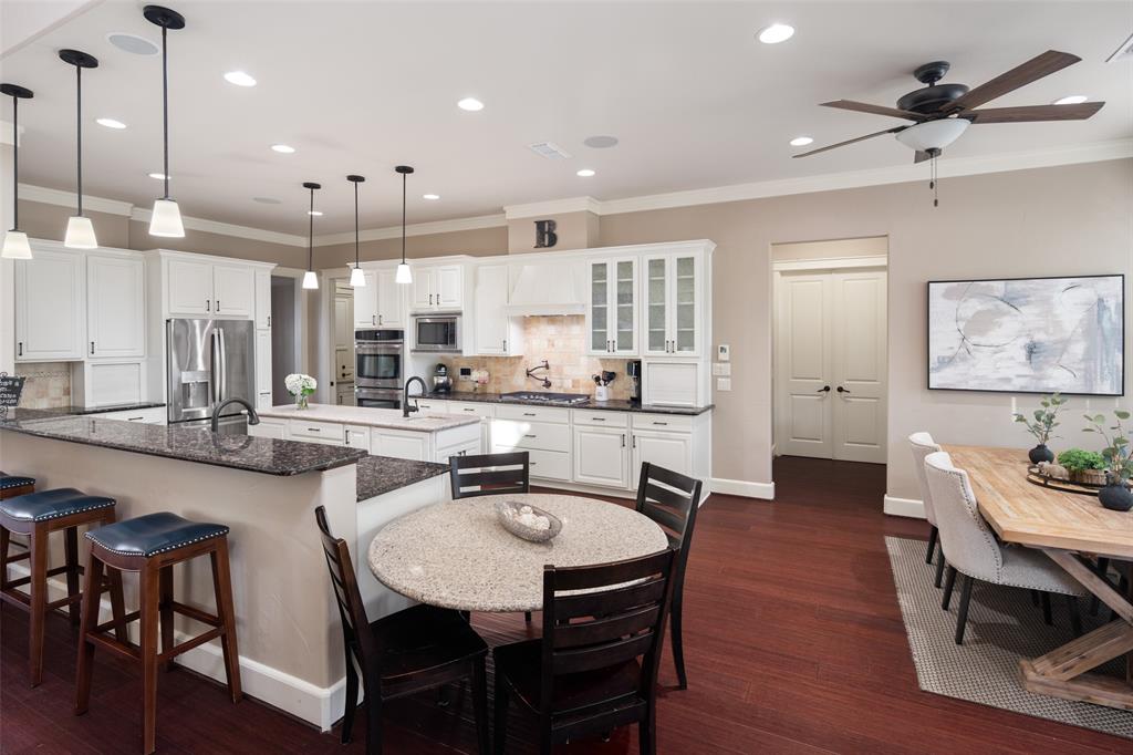 1814 Stacy Road Fairview, TX 75069 - Photo 13 of 36 a kitchen with stainless steel appliances kitchen island granite countertop a table chairs and a refrigerator