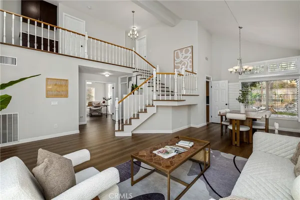 a dining room with wooden floor a chandelier a wooden table and chairs