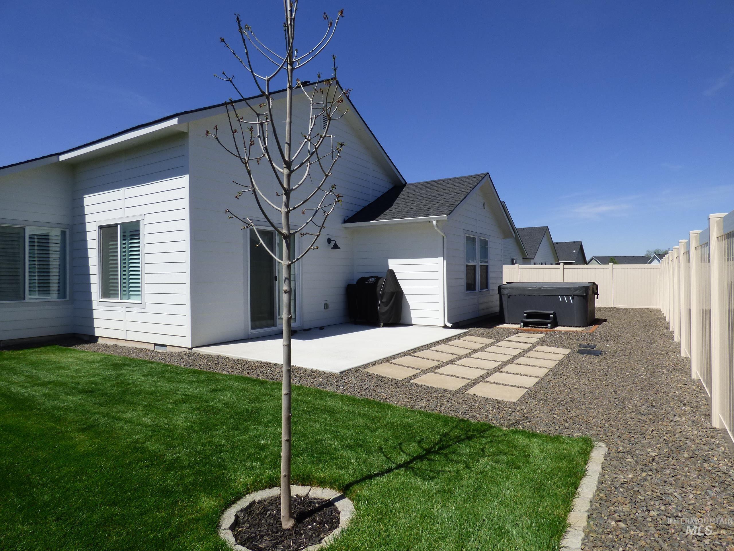 2708 East Buckaroo Drive Kuna, ID 83634 - Photo 38 of 48 Expansive rear yard featuring a concrete patio, stepping stone pathway, and a hot tub