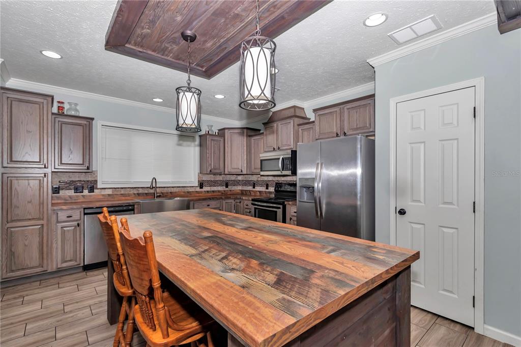 7565 Dewey Robbins Road Howey-in-the-Hills, FL 34737 - Photo 12 of 42 a kitchen with stainless steel appliances granite countertop a kitchen island a stove a refrigerator a sink a dining table and chairs